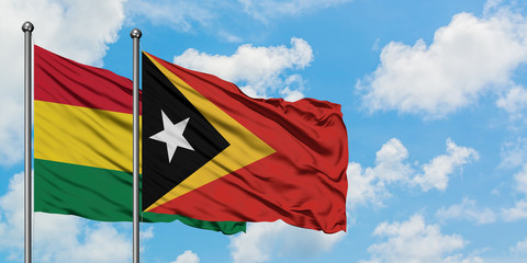 Bolivia and East Timor flag waving in the wind against white cloudy blue sky together. Diplomacy concept, international relations.
