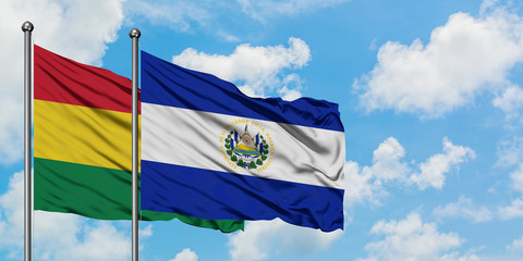 Bolivia and El Salvador flag waving in the wind against white cloudy blue sky together. Diplomacy concept, international relations.