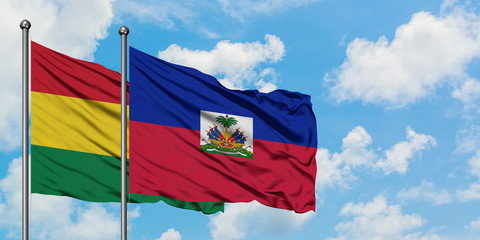 Bolivia and Haiti flag waving in the wind against white cloudy blue sky together. Diplomacy...