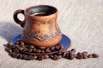 Mug of coffee with beans on burlap