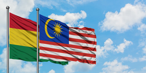 Bolivia and Malaysia flag waving in the wind against white cloudy blue sky together. Diplomacy concept, international relations.