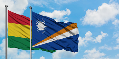Bolivia and Marshall Islands flag waving in the wind against white cloudy blue sky together....