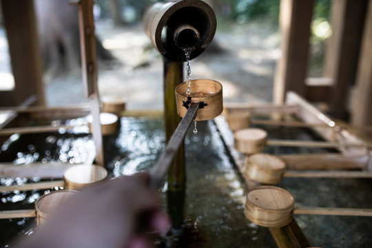 Young woman catching water for the ritual of hand washing in a Tokyo temple, Japan