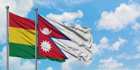 Bolivia and Nepal flag waving in the wind against white cloudy blue sky together. Diplomacy concept, international relations.