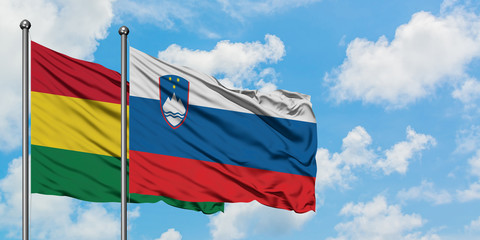 Bolivia and Slovenia flag waving in the wind against white cloudy blue sky together. Diplomacy concept, international relations.
