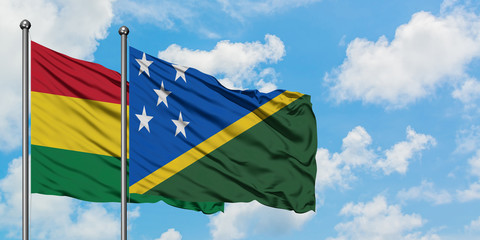 Bolivia and Solomon Islands flag waving in the wind against white cloudy blue sky together. Diplomacy concept, international relations.