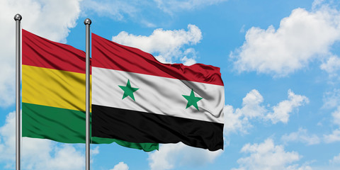 Bolivia and Syria flag waving in the wind against white cloudy blue sky together. Diplomacy...
