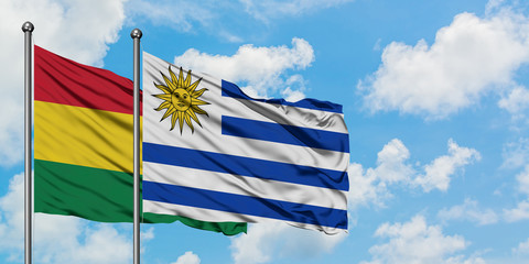 Bolivia and Uruguay flag waving in the wind against white cloudy blue sky together. Diplomacy concept, international relations.