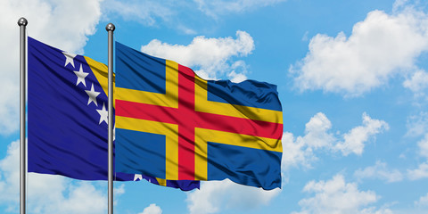 Bosnia Herzegovina and Aland Islands flag waving in the wind against white cloudy blue sky...