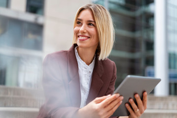 Smiling young businesswoman using tablet in the city