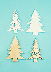 Wooden decorative Christmas trees on a blue background with sparkles. Hanging Christmas decorations.