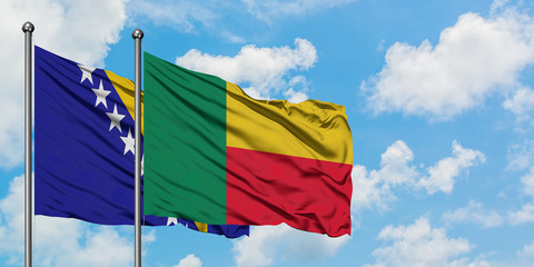 Bosnia Herzegovina and Benin flag waving in the wind against white cloudy blue sky together....
