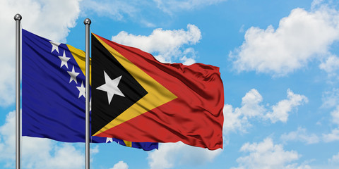 Bosnia Herzegovina and East Timor flag waving in the wind against white cloudy blue sky together. Diplomacy concept, international relations.