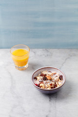 Bowl of granola with yogurt, nuts, raisins, cranberries and chia seeds. Concept for a tasty and healthy meal. Stone - wooden background.Copy space.