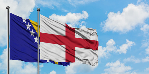 Bosnia Herzegovina and England flag waving in the wind against white cloudy blue sky together. Diplomacy concept, international relations.