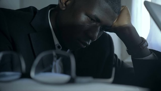 Stressed overworked american african man in his office at night