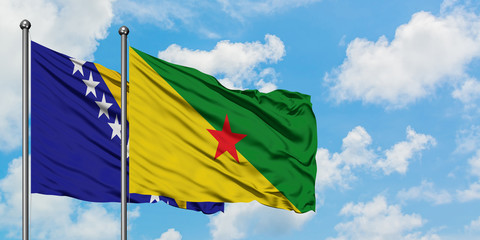 Bosnia Herzegovina and French Guiana flag waving in the wind against white cloudy blue sky together. Diplomacy concept, international relations.