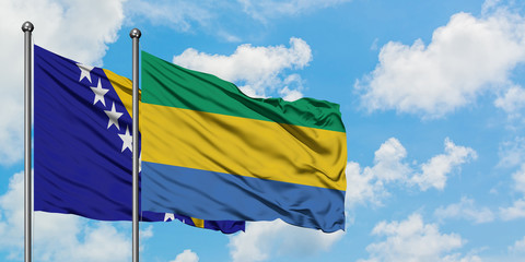 Bosnia Herzegovina and Gabon flag waving in the wind against white cloudy blue sky together....