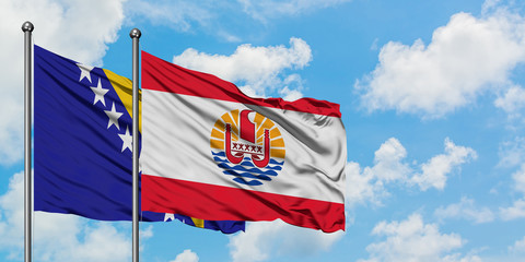 Bosnia Herzegovina and French Polynesia flag waving in the wind against white cloudy blue sky...