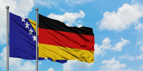 Bosnia Herzegovina and Germany flag waving in the wind against white cloudy blue sky together. Diplomacy concept, international relations.