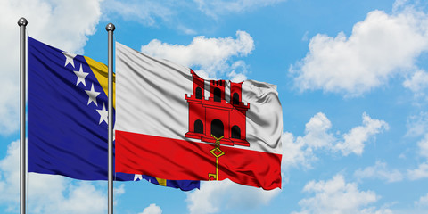 Bosnia Herzegovina and Gibraltar flag waving in the wind against white cloudy blue sky together....