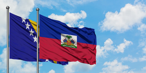 Bosnia Herzegovina and Haiti flag waving in the wind against white cloudy blue sky together. Diplomacy concept, international relations.