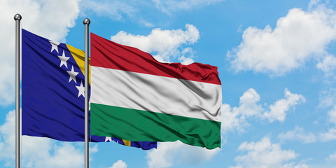 Bosnia Herzegovina and Hungary flag waving in the wind against white cloudy blue sky together. Diplomacy concept, international relations.