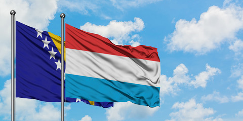 Bosnia Herzegovina and Luxembourg flag waving in the wind against white cloudy blue sky together. Diplomacy concept, international relations.