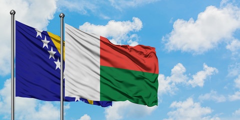 Bosnia Herzegovina and Madagascar flag waving in the wind against white cloudy blue sky together. Diplomacy concept, international relations.