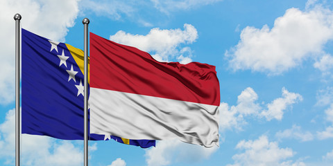 Bosnia Herzegovina and Monaco flag waving in the wind against white cloudy blue sky together. Diplomacy concept, international relations.