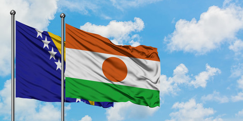 Bosnia Herzegovina and Niger flag waving in the wind against white cloudy blue sky together....