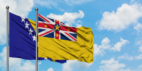 Bosnia Herzegovina and Niue flag waving in the wind against white cloudy blue sky together. Diplomacy concept, international relations.
