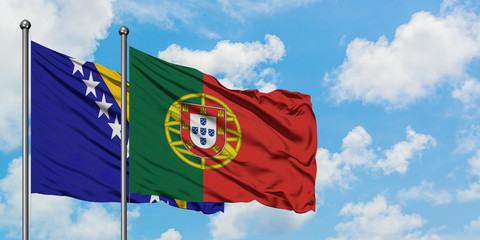 Bosnia Herzegovina and Portugal flag waving in the wind against white cloudy blue sky together. Diplomacy concept, international relations.