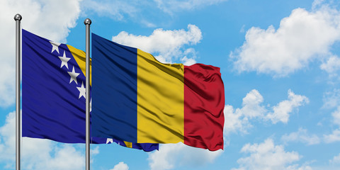 Bosnia Herzegovina and Romania flag waving in the wind against white cloudy blue sky together. Diplomacy concept, international relations.
