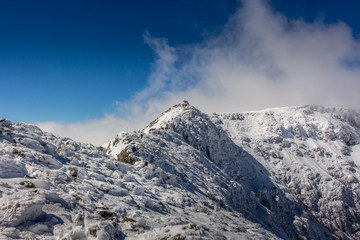 Hiking to the Maliovica summit after a cold winter storm at the Rila mountain in Bulgaria,...