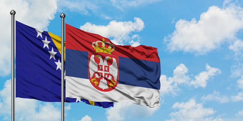 Bosnia Herzegovina and Serbia flag waving in the wind against white cloudy blue sky together. Diplomacy concept, international relations.