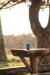 Mug of hot coffee in a cardboard cup on a wooden table. Coffee to go outdoors