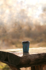 Mug of hot coffee in a cardboard cup on a wooden table. Coffee to go outdoors