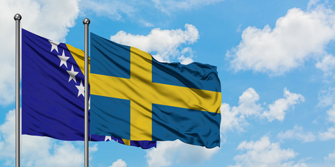 Bosnia Herzegovina and Sweden flag waving in the wind against white cloudy blue sky together. Diplomacy concept, international relations.