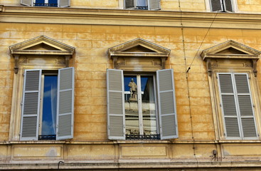 Yellow neoclassical building with sculpture reflection on a window. Rome, Italy.