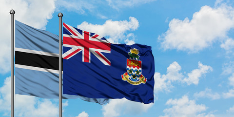 Botswana and Cayman Islands flag waving in the wind against white cloudy blue sky together. Diplomacy concept, international relations.