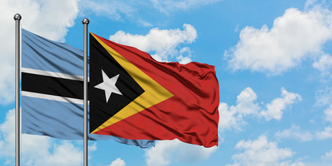 Botswana and East Timor flag waving in the wind against white cloudy blue sky together. Diplomacy concept, international relations.