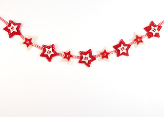 Christmas garland with carved red felt stars on white yellow background. Concept for greeting cards, invitations with copy space