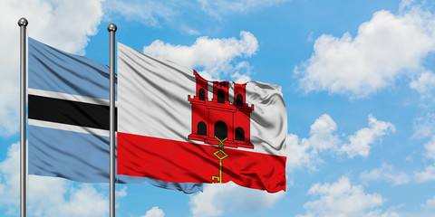Botswana and Gibraltar flag waving in the wind against white cloudy blue sky together. Diplomacy concept, international relations.