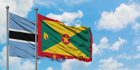 Botswana and Grenada flag waving in the wind against white cloudy blue sky together. Diplomacy concept, international relations.