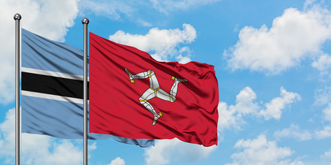 Botswana and Isle Of Man flag waving in the wind against white cloudy blue sky together. Diplomacy concept, international relations.