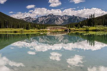 Cascade Pond with foot bridge and mountains reflecting in pond in Banff National Park, Alberta, Canada