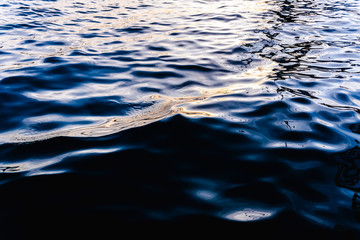 Waves on the surface of the sea water at dusk with compact, solid and deeply calm texture.