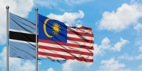 Botswana and Malaysia flag waving in the wind against white cloudy blue sky together. Diplomacy concept, international relations.
