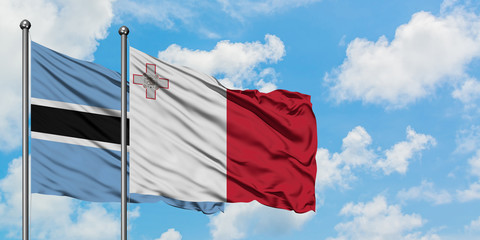 Botswana and Malta flag waving in the wind against white cloudy blue sky together. Diplomacy concept, international relations.